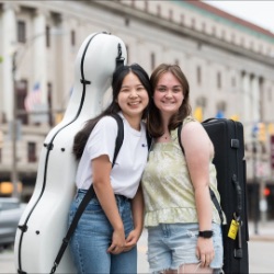罗彻斯特大学前，两名学生背着乐器箱，摆姿势微笑, 伊士曼音乐学院. 